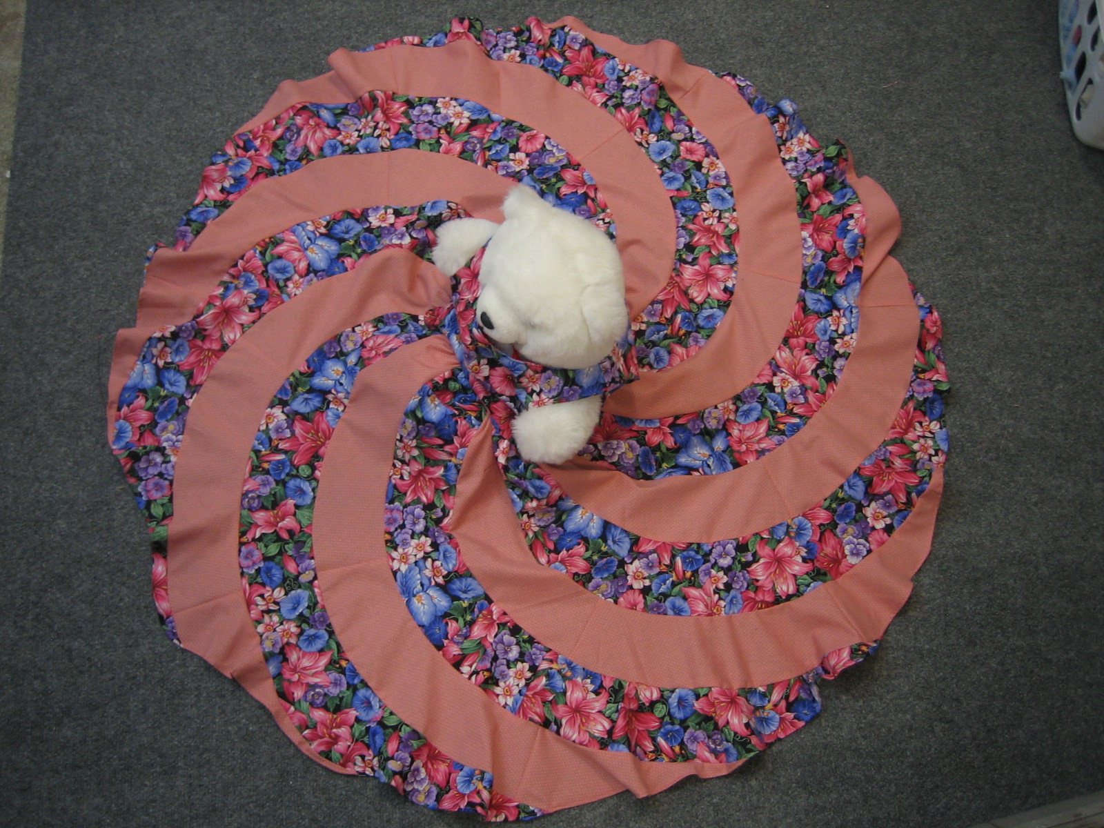 View from the ceiling of full circle spiral swirl dress, modeled by a white teddy bear. 